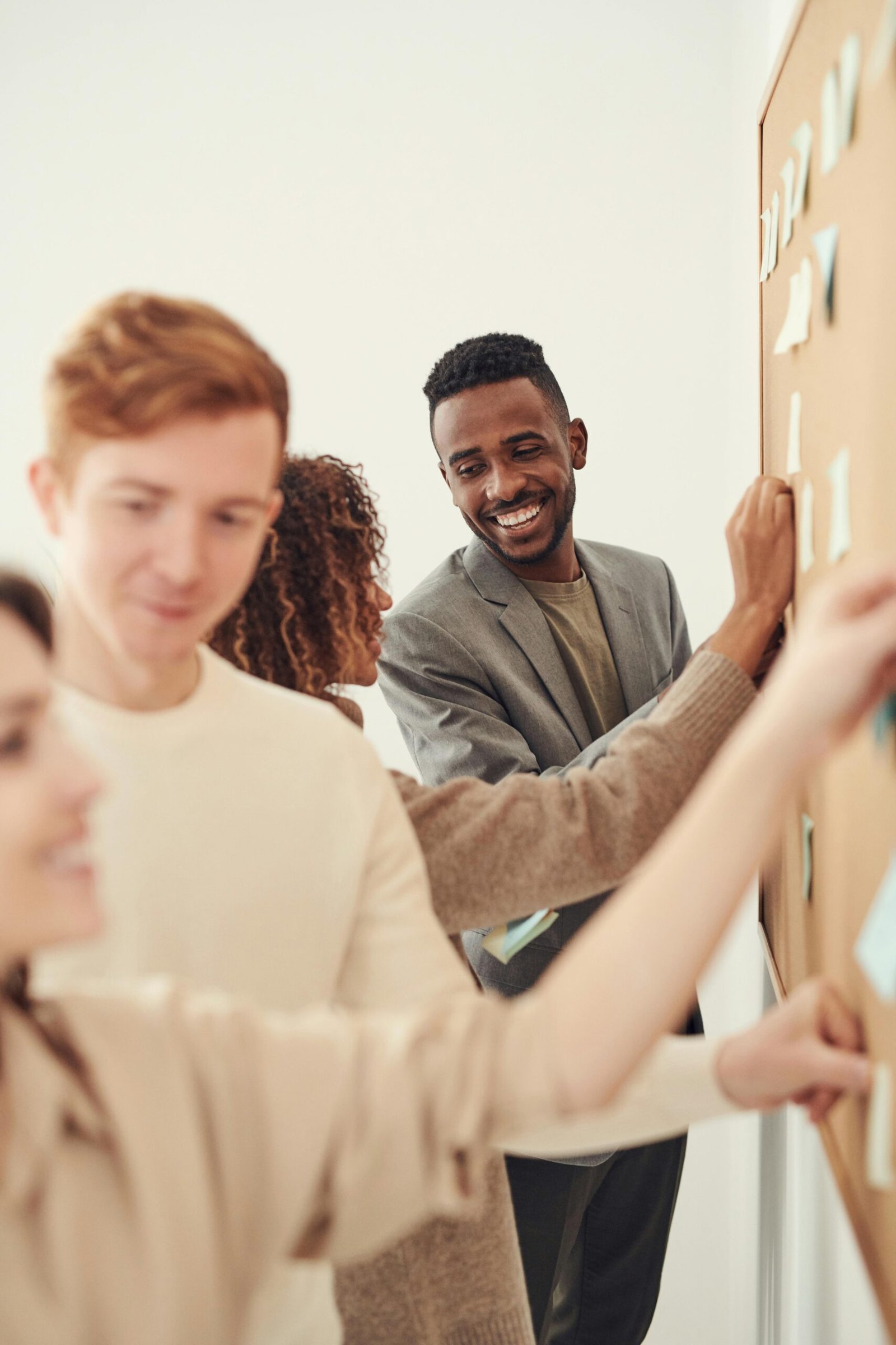 A diverse group of professionals collaborating on a project by using sticky notes on a board indoors.